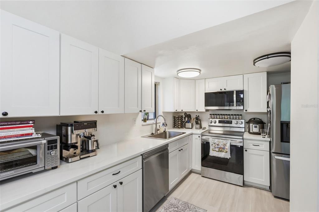 A kitchen features white cabinets, stainless steel appliances, and white countertops — 200 FAIRWAY DRIVE UNIT 200, LONGWOOD, FL