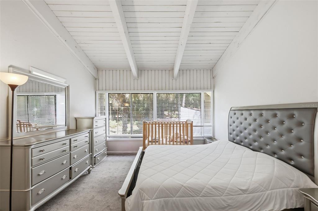 A bedroom features a tufted headboard, a dresser with a mirror, and a wooden crib — 200 FAIRWAY DRIVE UNIT 200, LONGWOOD, FL