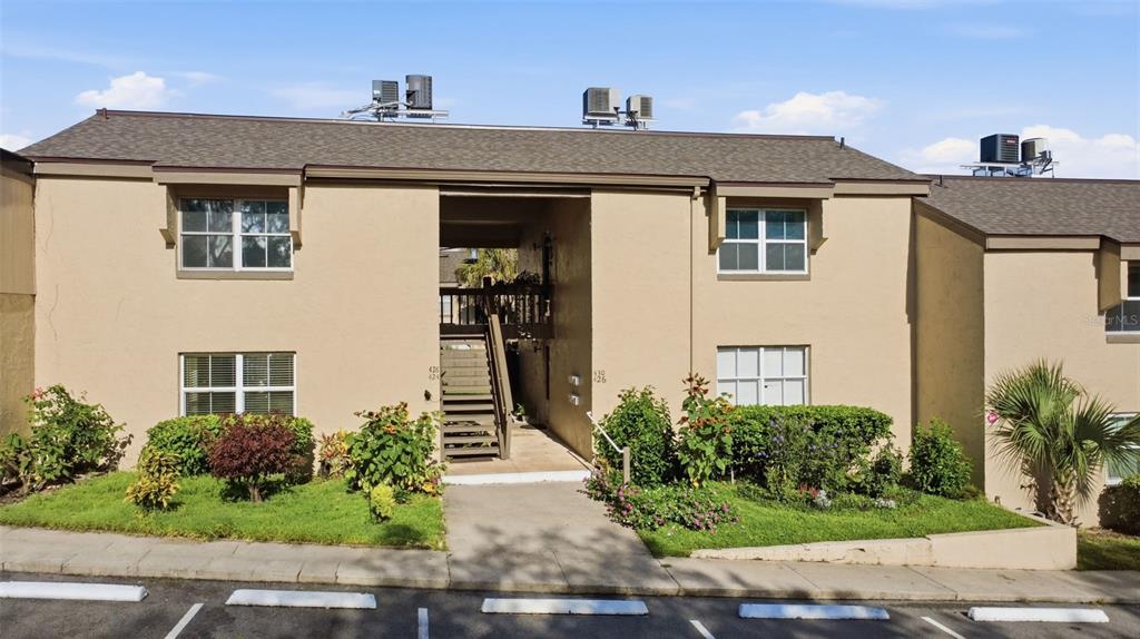 A two-story tan apartment building with a central staircase and a parking lot in front — 430 WINDMEADOWS STREET, ALTAMONTE SPRINGS, FL
