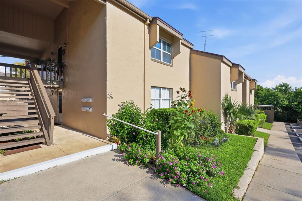 A tan two-story apartment building exterior features an outdoor staircase and a landscaped garden bed — 430 WINDMEADOWS STREET, ALTAMONTE SPRINGS, FL