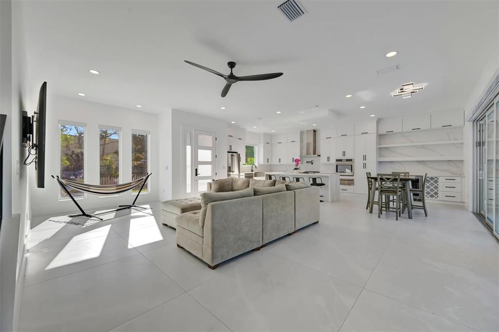 A bright, open-concept living room and kitchen featuring white tile floors and a hammock — 3723 NORWOOD COURT, SARASOTA, FL