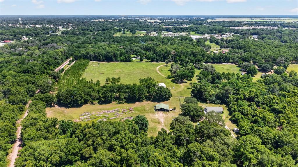 An aerial view shows a rural property with a house, barn, and surrounding wooded land — 12176 SE US HWY 441 HIGHWAY, BELLEVIEW, FL