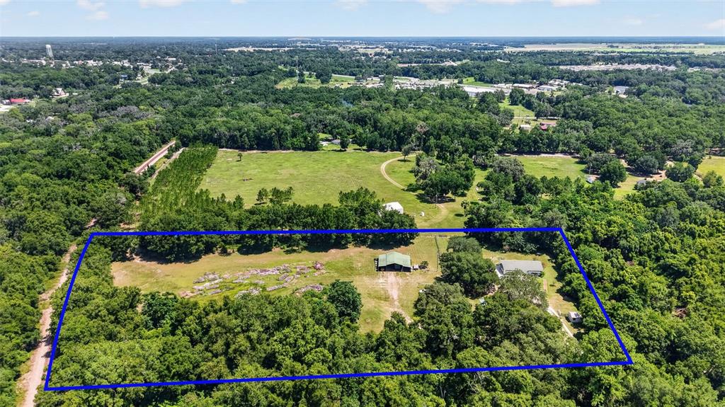 An aerial view shows a rural property with two buildings surrounded by trees and fields — 12176 SE US HWY 441 HIGHWAY, BELLEVIEW, FL