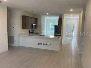 A kitchen with dark wood cabinets and a white island overlooks an open living area — 4035 BRUING STREET, NORTH PORT, FL