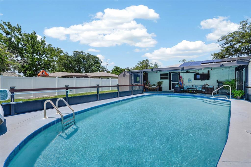 A backyard swimming pool with a metal fence and a covered patio area — 792 N BEACH STREET, ORMOND BEACH, FL