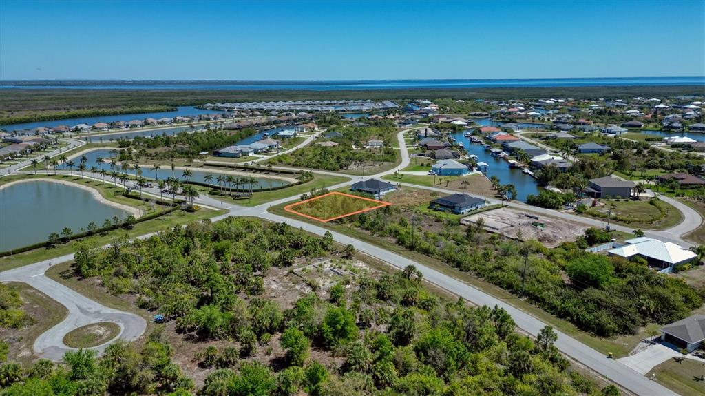 An aerial view shows a vacant, rectangular residential lot outlined in orange within a neighborhood — 8062 CAROLINE DRIVE, PORT CHARLOTTE, FL