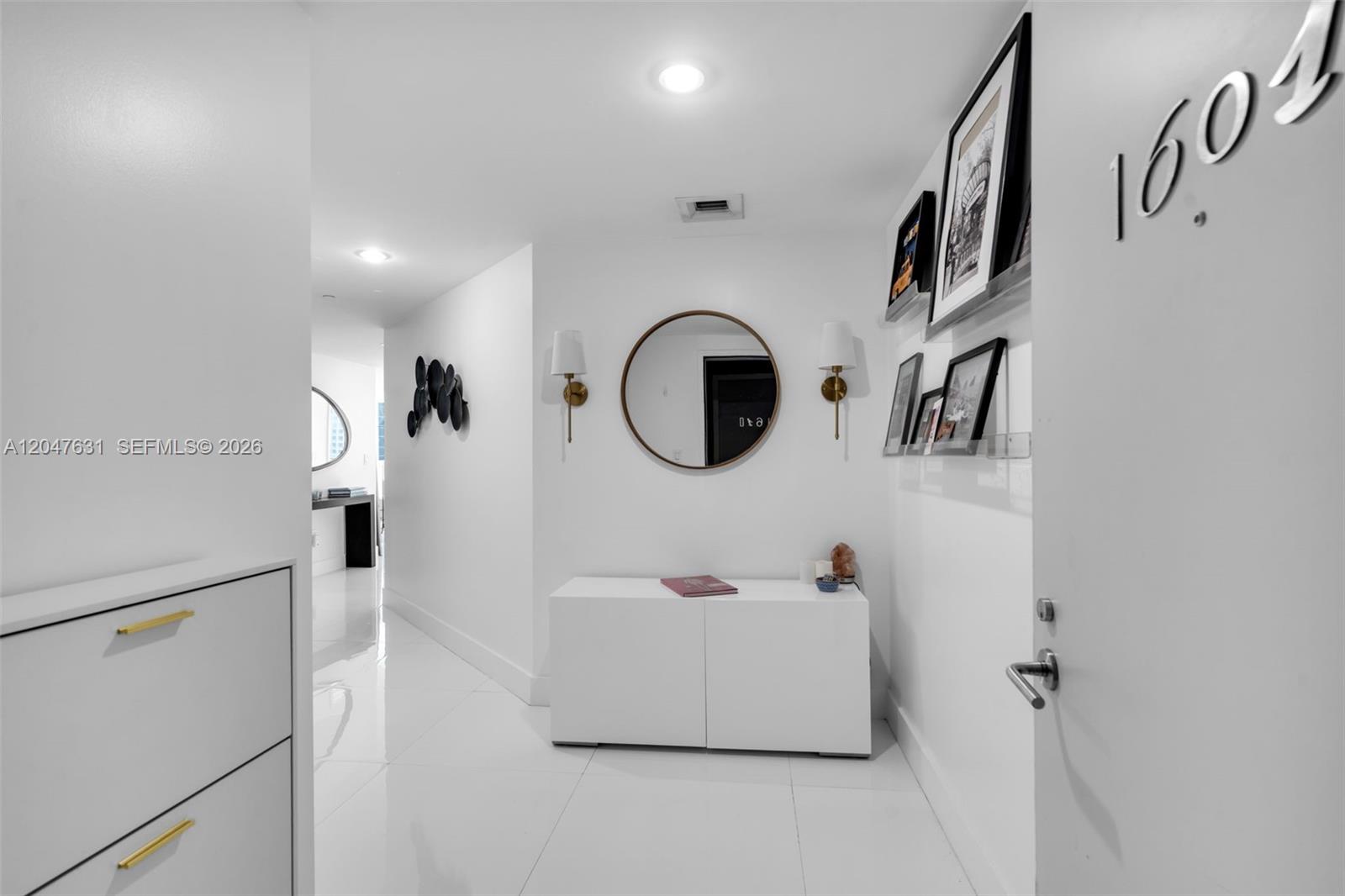 A modern white entryway features a round mirror, wall sconces, and a sleek console table — 1300 S Miami Ave # 1601, Miami FL 33130, MIAMI, FL