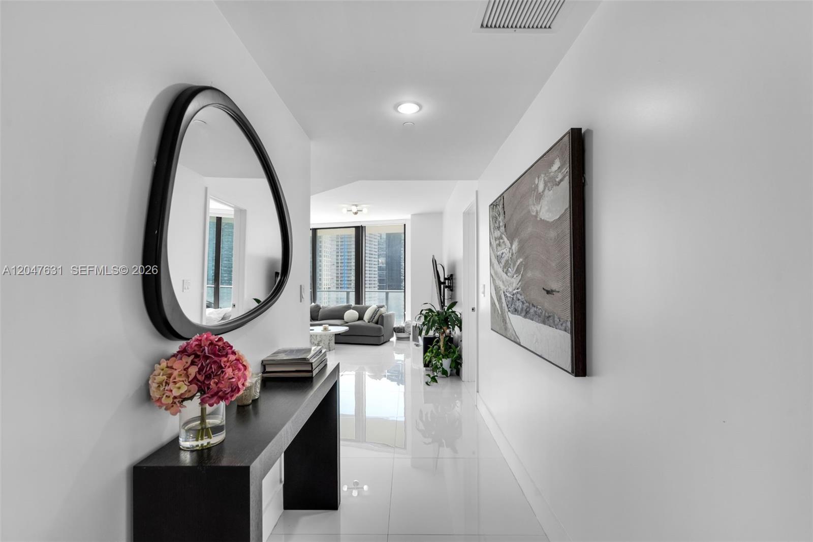 A bright hallway with white floors leads to a living area with city views — 1300 S Miami Ave # 1601, Miami FL 33130, MIAMI, FL