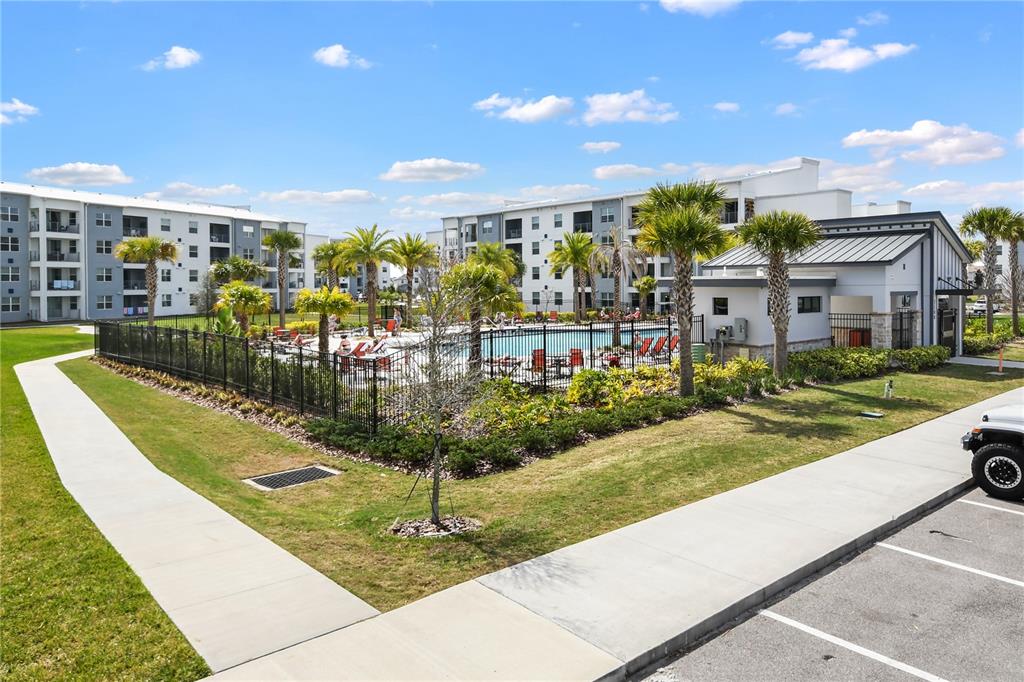 An outdoor swimming pool area with palm trees and lounge chairs next to apartment buildings — 3191 PARADOX CIRCLE UNIT 401, KISSIMMEE, FL