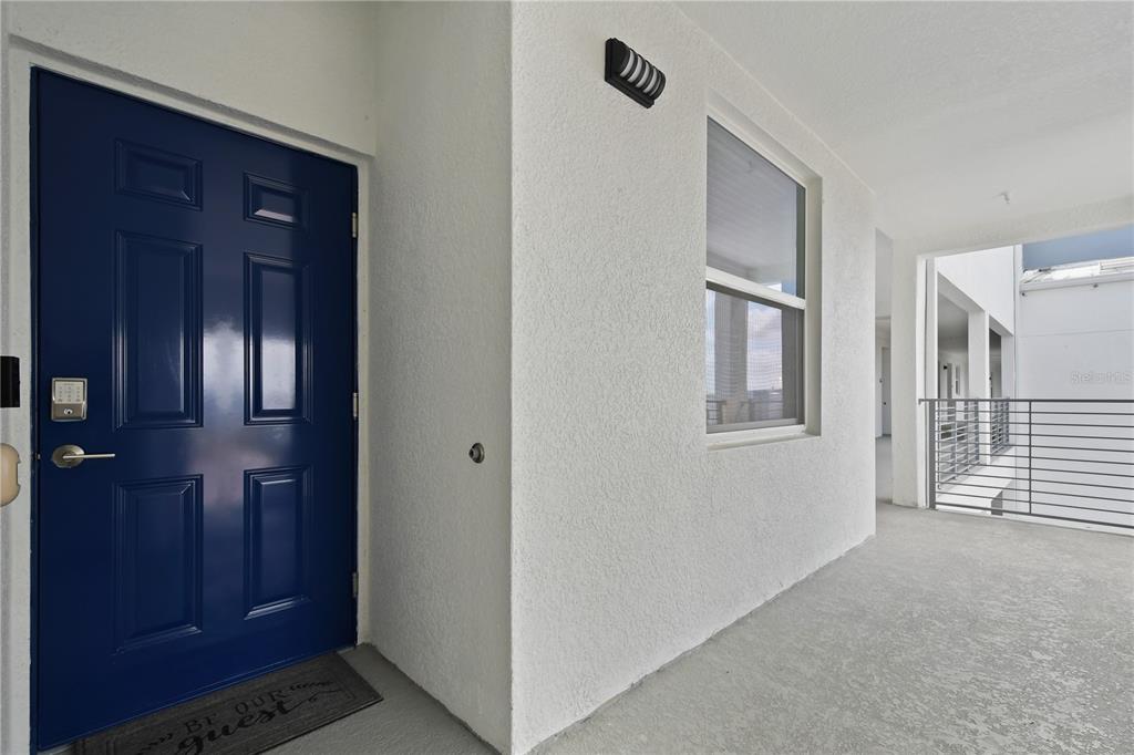 A blue front door with a keypad lock opens onto a concrete balcony with railings — 3191 PARADOX CIRCLE UNIT 401, KISSIMMEE, FL