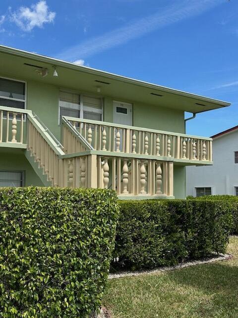 A light green two-story building features a tan balustrade balcony and a staircase — 72 Norwich C, West Palm Beach FL 33417, WEST PALM BEACH, FL
