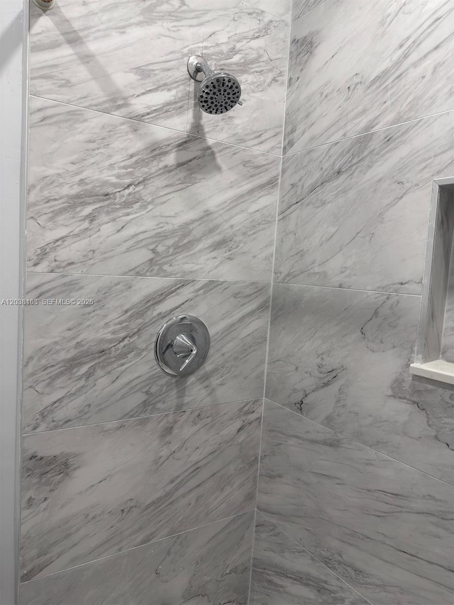 A shower features marble-look wall tiles, a chrome showerhead, and a single-handle mixing valve — 214 SW 2nd Ter, Dania Beach FL 33004, DANIA BEACH, FL