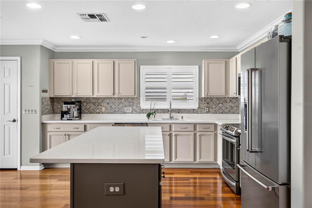 A kitchen features light cabinets, a dark island, stainless steel appliances, and hardwood flooring — 3351 LINTOWER DRIVE, LAND O LAKES, FL