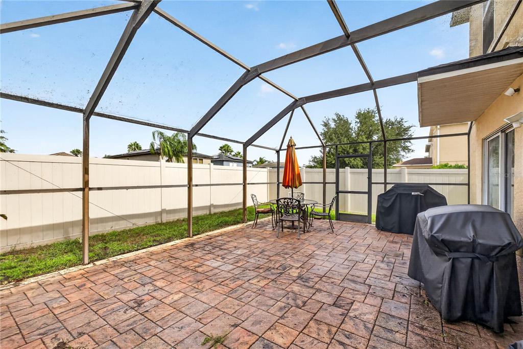 A screened-in patio features a paved floor, outdoor dining set, and two covered grills — 3351 LINTOWER DRIVE, LAND O LAKES, FL