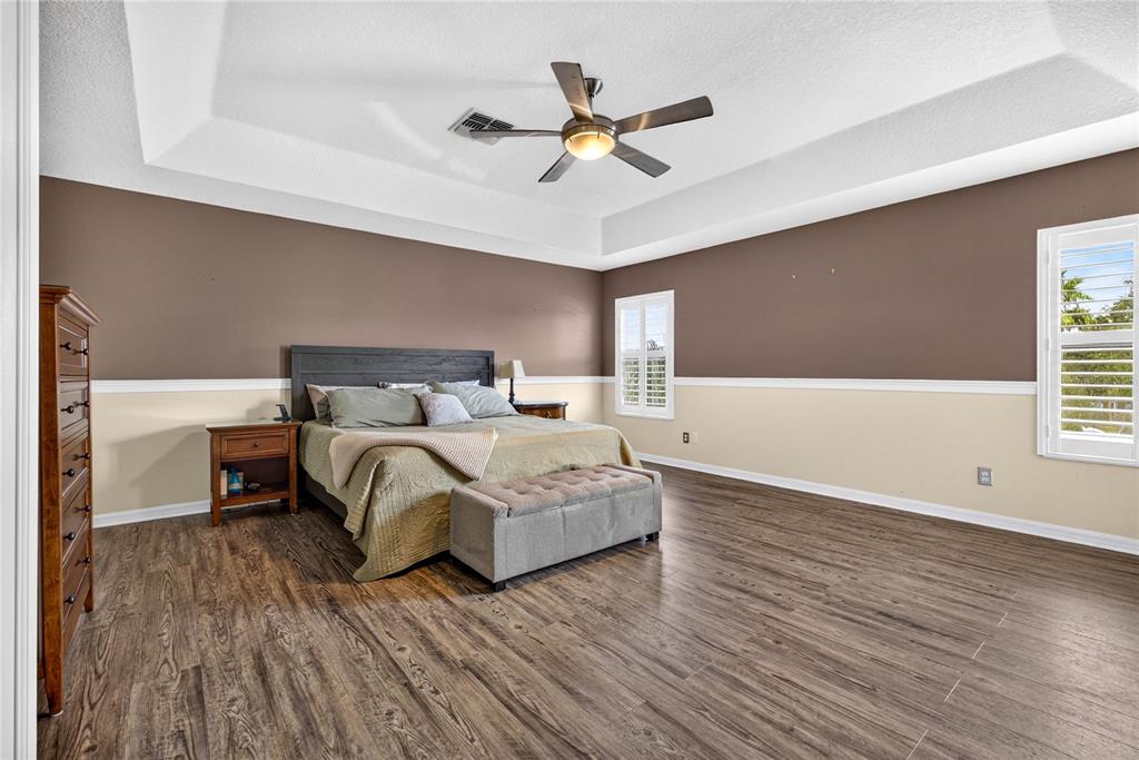 A bedroom with wood-look flooring, a tray ceiling, and two-toned walls with chair rail molding — 3351 LINTOWER DRIVE, LAND O LAKES, FL