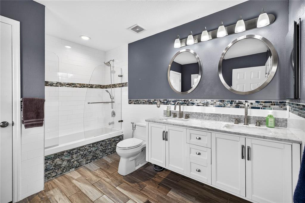 A bathroom features a double vanity, a tub-shower combination, and dark gray accent walls — 3351 LINTOWER DRIVE, LAND O LAKES, FL