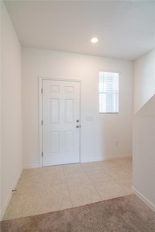 An entryway features a white door, a window with blinds, tile flooring, and carpet — 205 MANDOVI STREET, DAVENPORT, FL