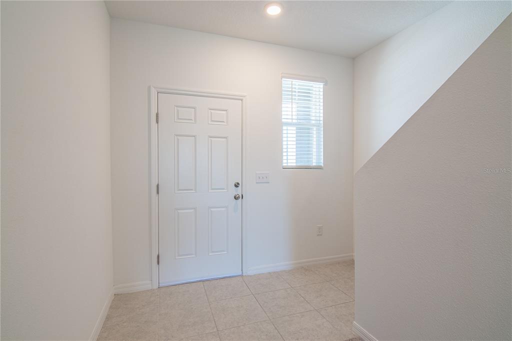 An entryway features a white door, a window with blinds, and light-colored tile flooring — 205 MANDOVI STREET, DAVENPORT, FL