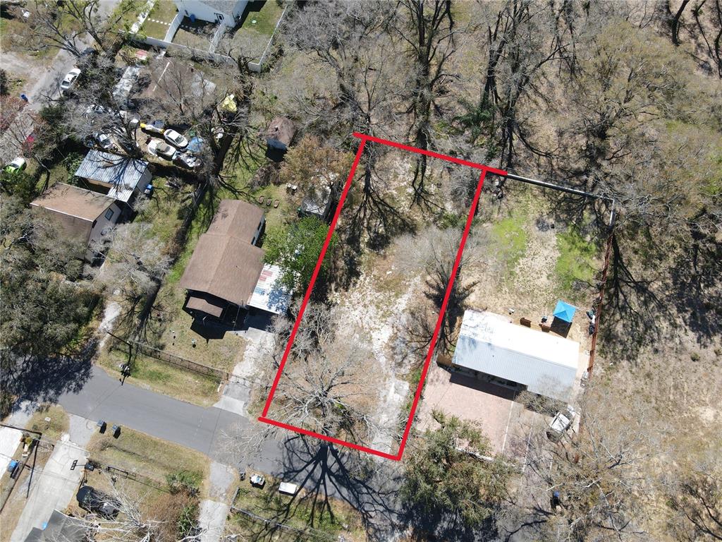 An aerial view shows a vacant rectangular lot outlined in red between two residential properties — 7207 RHODE ISLAND DRIVE, TAMPA, FL