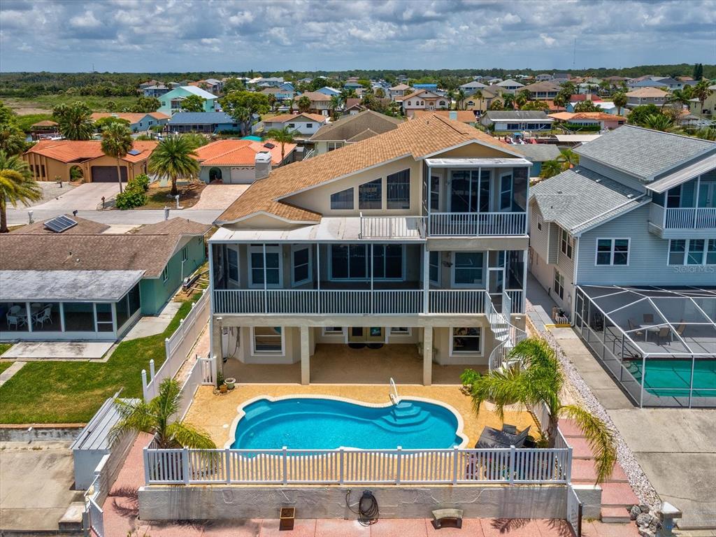 An aerial view of a multi-story house featuring a swimming pool and screened-in balconies — 15709 CENTURY DRIVE, HUDSON, FL