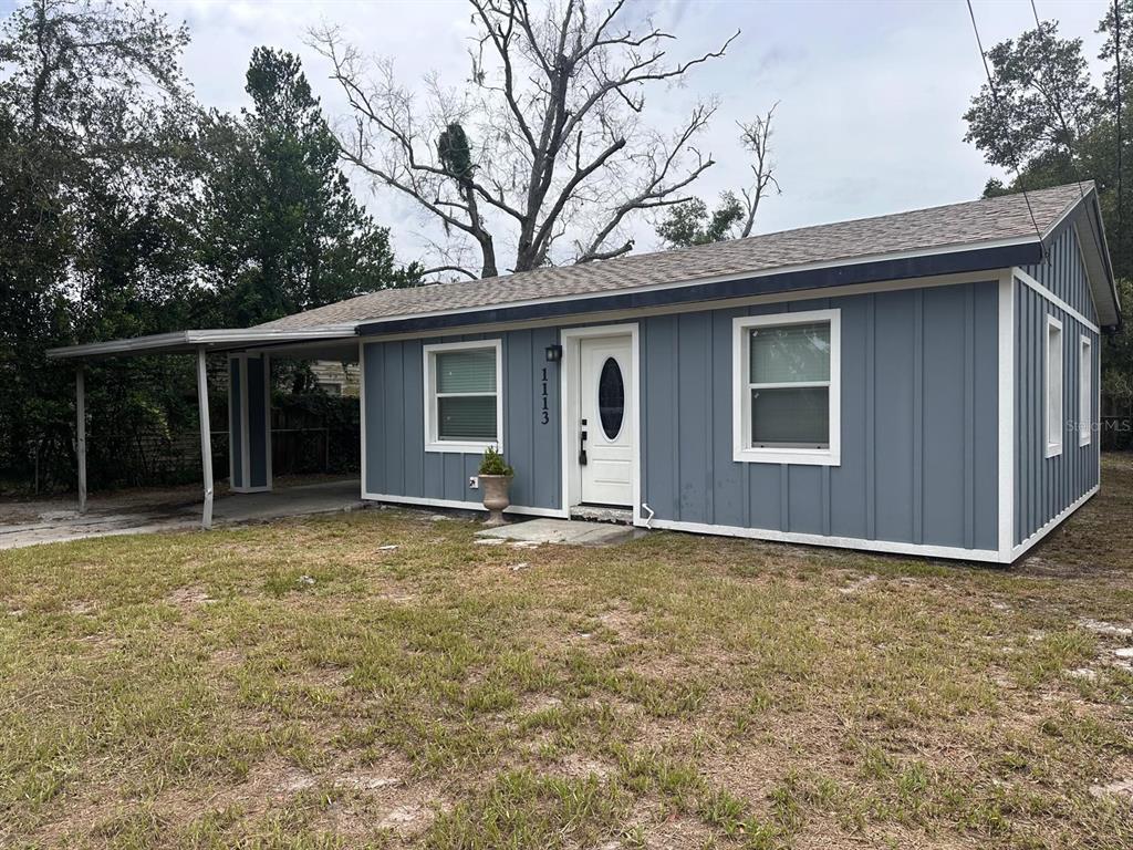 A single-story house with blue vertical siding, a white front door, and a metal carport — 1113 S CENTRAL AVENUE, LAKELAND, FL
