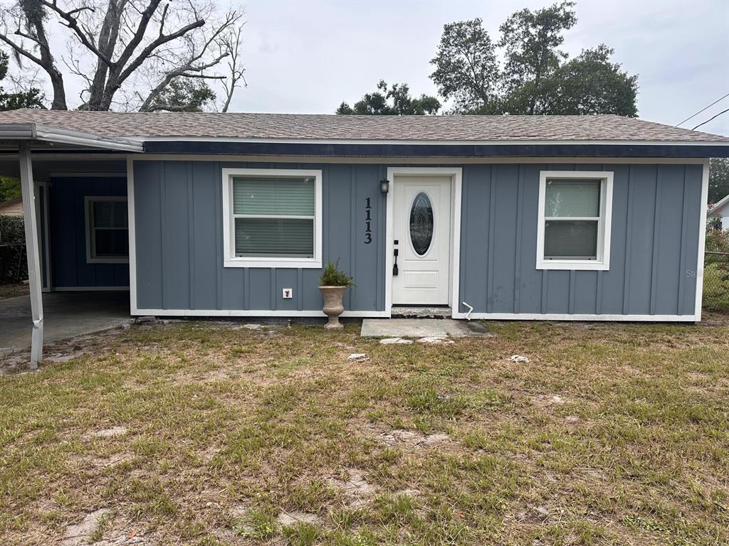 The exterior of a single-story house features blue vertical siding, a white door, and windows — 1113 S CENTRAL AVENUE, LAKELAND, FL