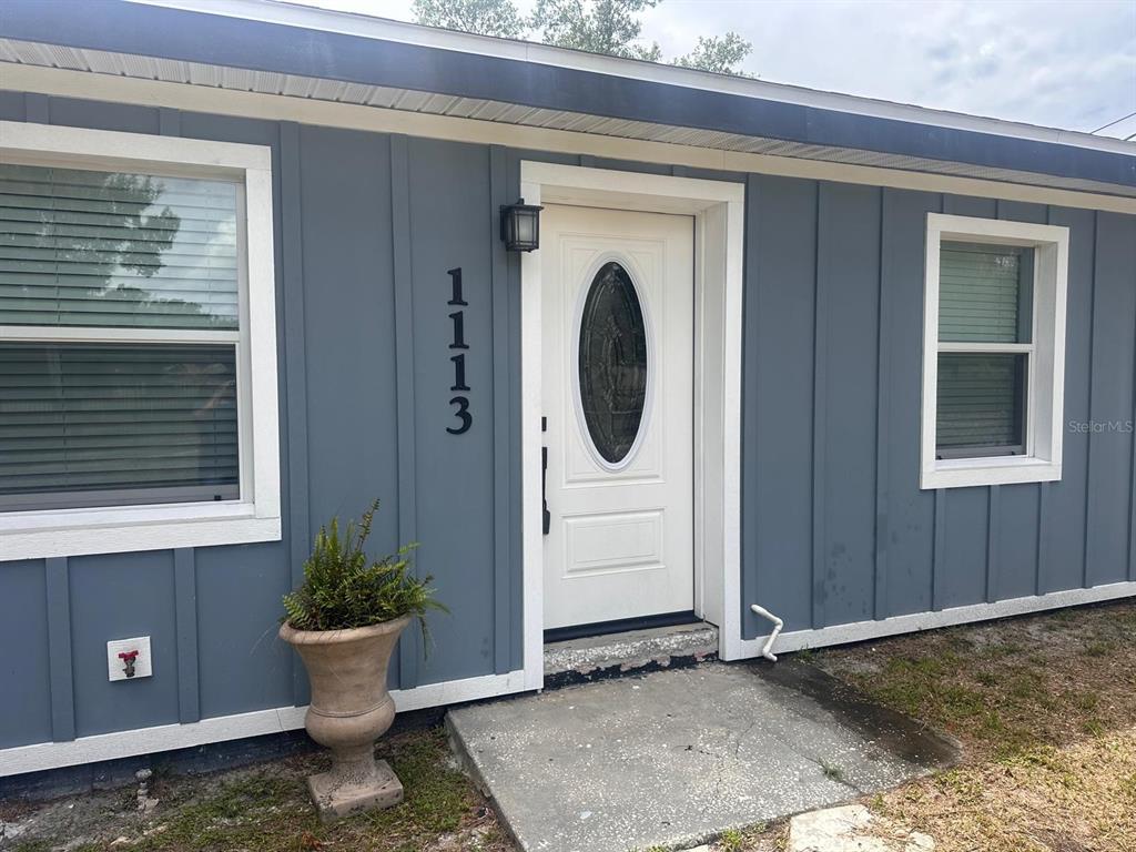 The exterior of a house features blue vertical siding, a white front door, and a planter — 1113 S CENTRAL AVENUE, LAKELAND, FL