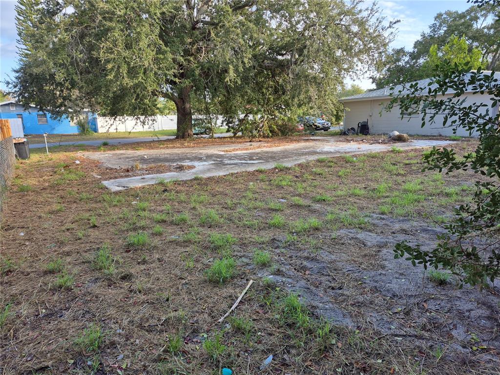 A large concrete slab sits in a grassy yard beneath a large tree — 7116 DIPAOLA DRIVE, HUDSON, FL