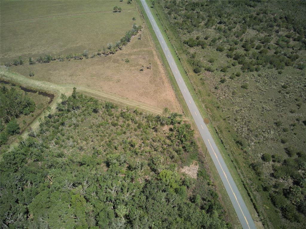 An aerial view shows a paved road running through a rural landscape of fields and woods — EMERALDA ISLAND ROAD, LEESBURG, FL