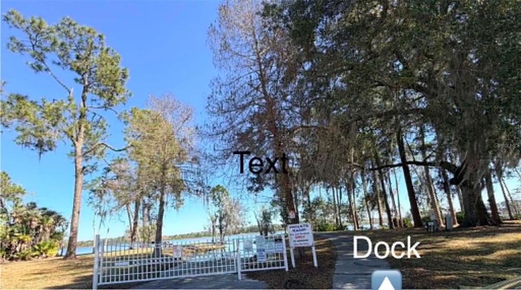 A concrete carport features a metal wheelchair ramp and a view of a residential street — 50989 HIGHWAY 27 UNIT 87, DAVENPORT, FL