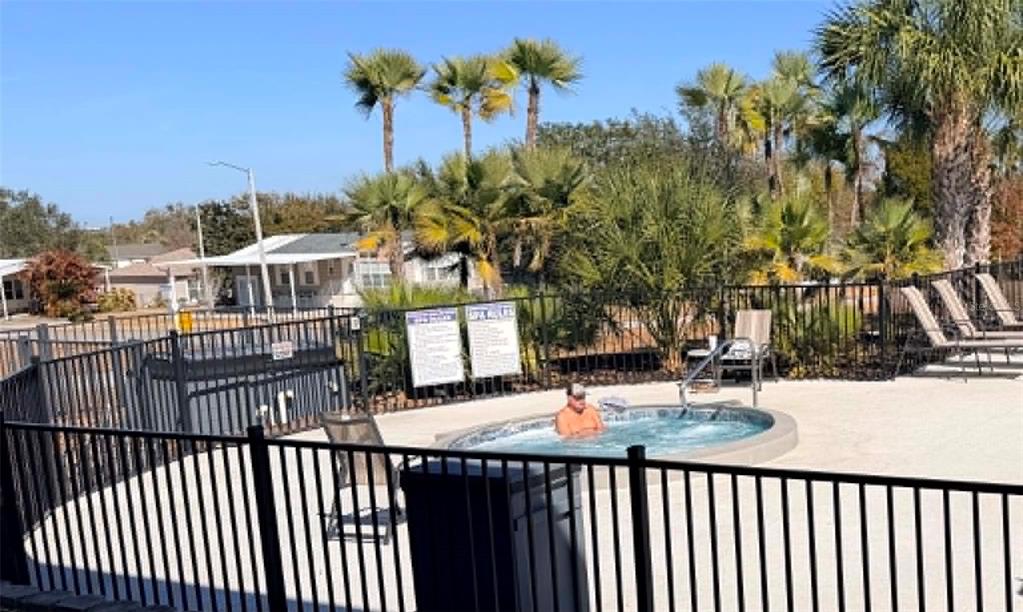 A sunroom features wood flooring, white horizontal siding, large windows, and a sliding glass door — 50989 HIGHWAY 27 UNIT 87, DAVENPORT, FL