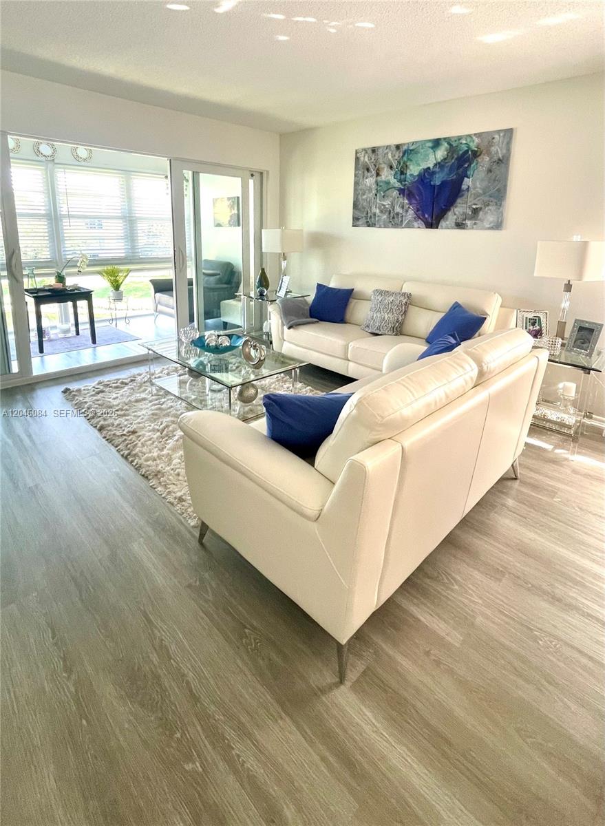 A living room features white leather sofas, a glass coffee table, and light wood flooring — 5980 NW 64th Ave # 312, Tamarac FL 33319, TAMARAC, FL
