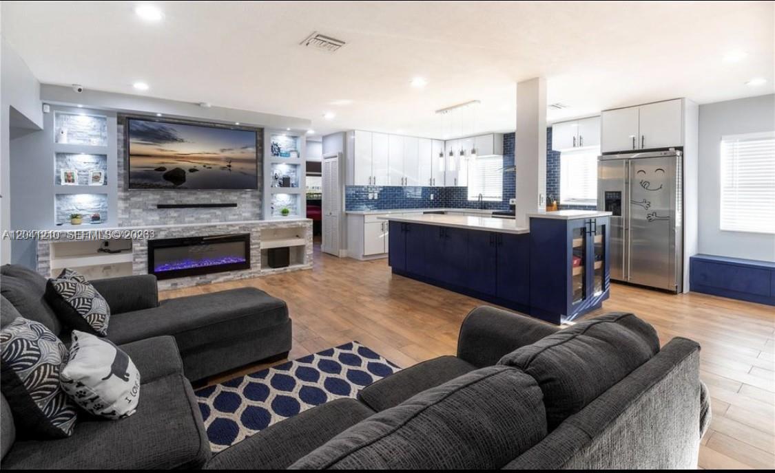 A swimming pool with a stone-tiled bar area sits in a fenced backyard — 16100 NE 9th Ct, North Miami Beach FL 33162, NORTH MIAMI BEACH, FL