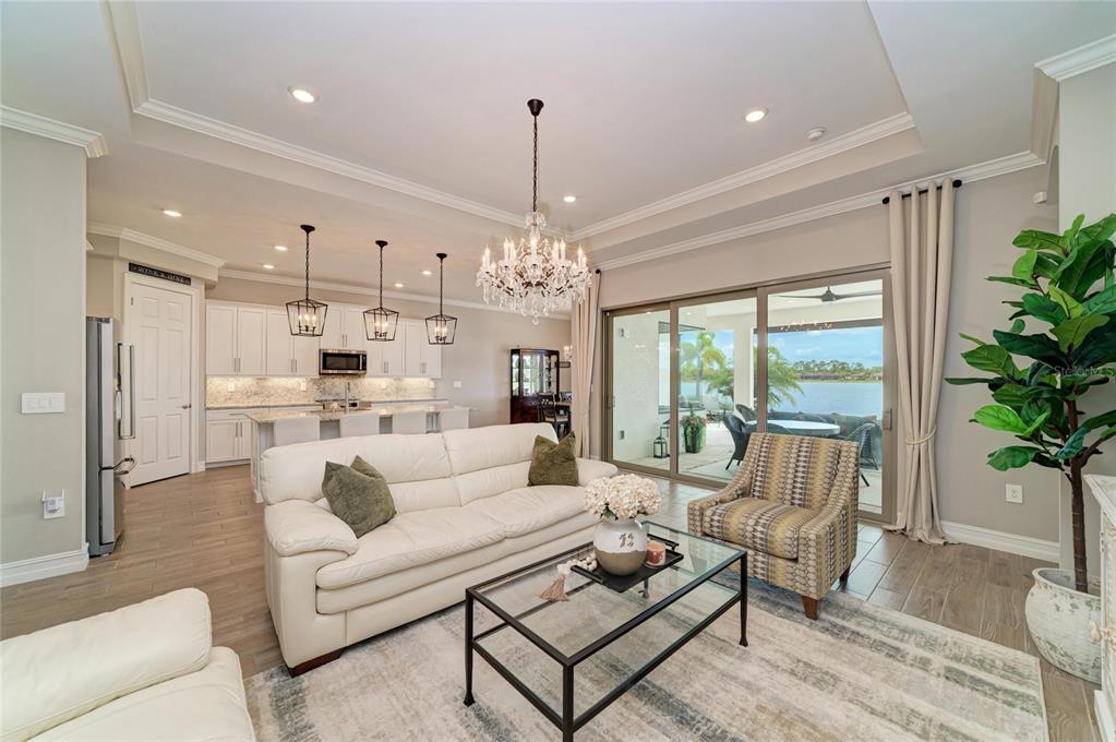 A living room with a white sofa, glass coffee table, and sliding doors overlooking a lake — 289 VILLORESI BOULEVARD, NOKOMIS, FL
