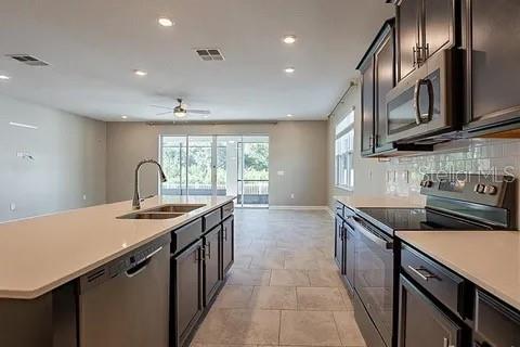 A modern kitchen features dark cabinetry, white countertops, a central island, and tile flooring — 4444 DESERT ROSE AVENUE, KISSIMMEE, FL
