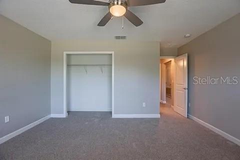 An empty bedroom with gray walls, beige carpeting, a ceiling fan, and an open closet — 4444 DESERT ROSE AVENUE, KISSIMMEE, FL