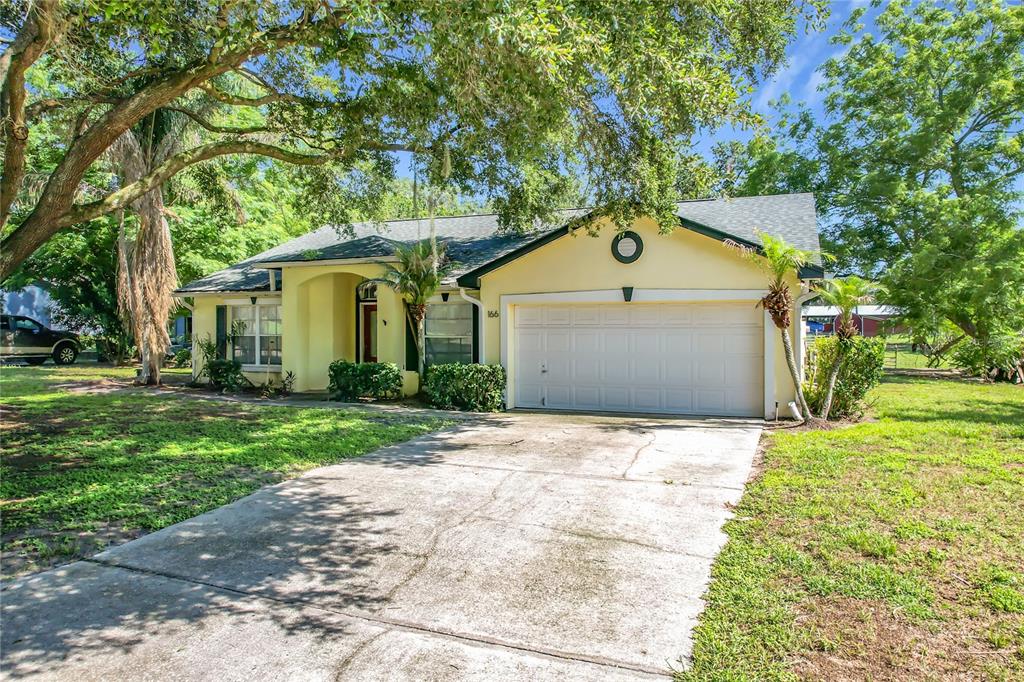 A yellow single-story house with a two-car garage and a concrete driveway — 166 BUCKHORN RUN, LAKELAND, FL