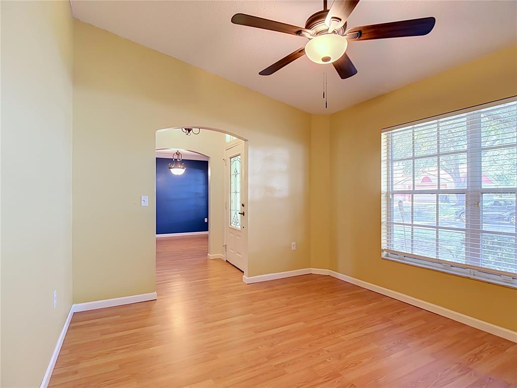 A room with light yellow walls, wood-look flooring, a ceiling fan, and a large window — 166 BUCKHORN RUN, LAKELAND, FL