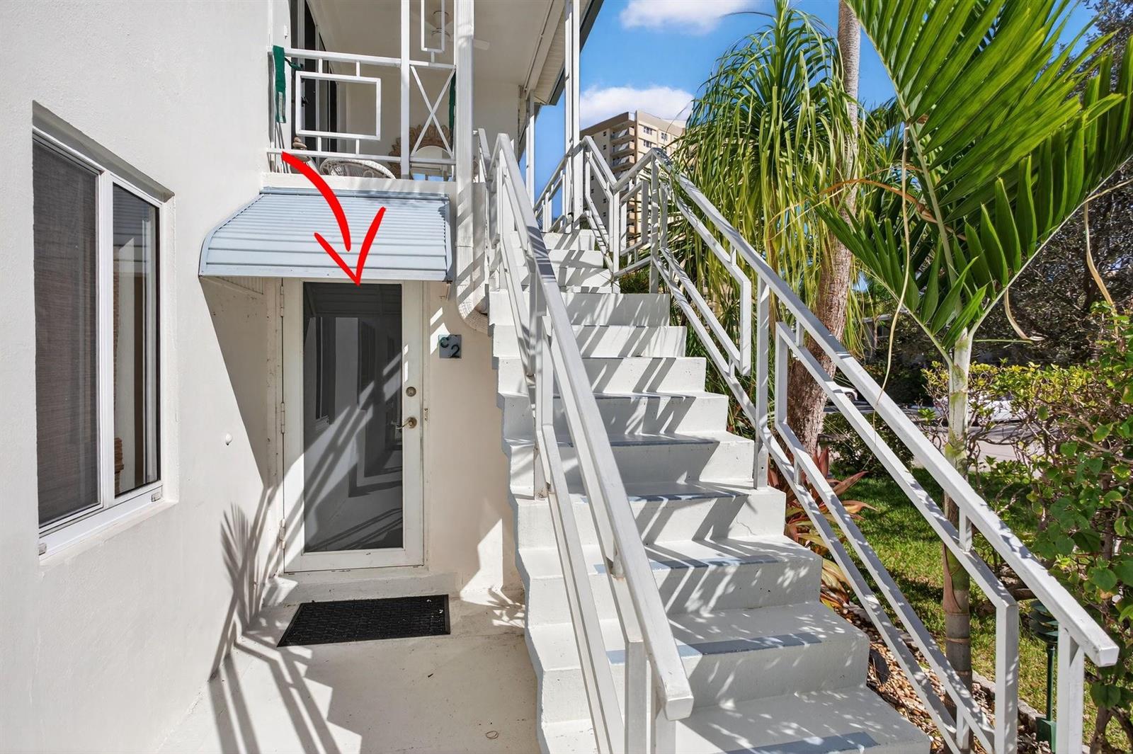 An exterior view of a white building entrance with a metal awning and stairs — 3201 SE 12th Street # C2, Pompano Beach FL 33062, POMPANO BEACH, FL