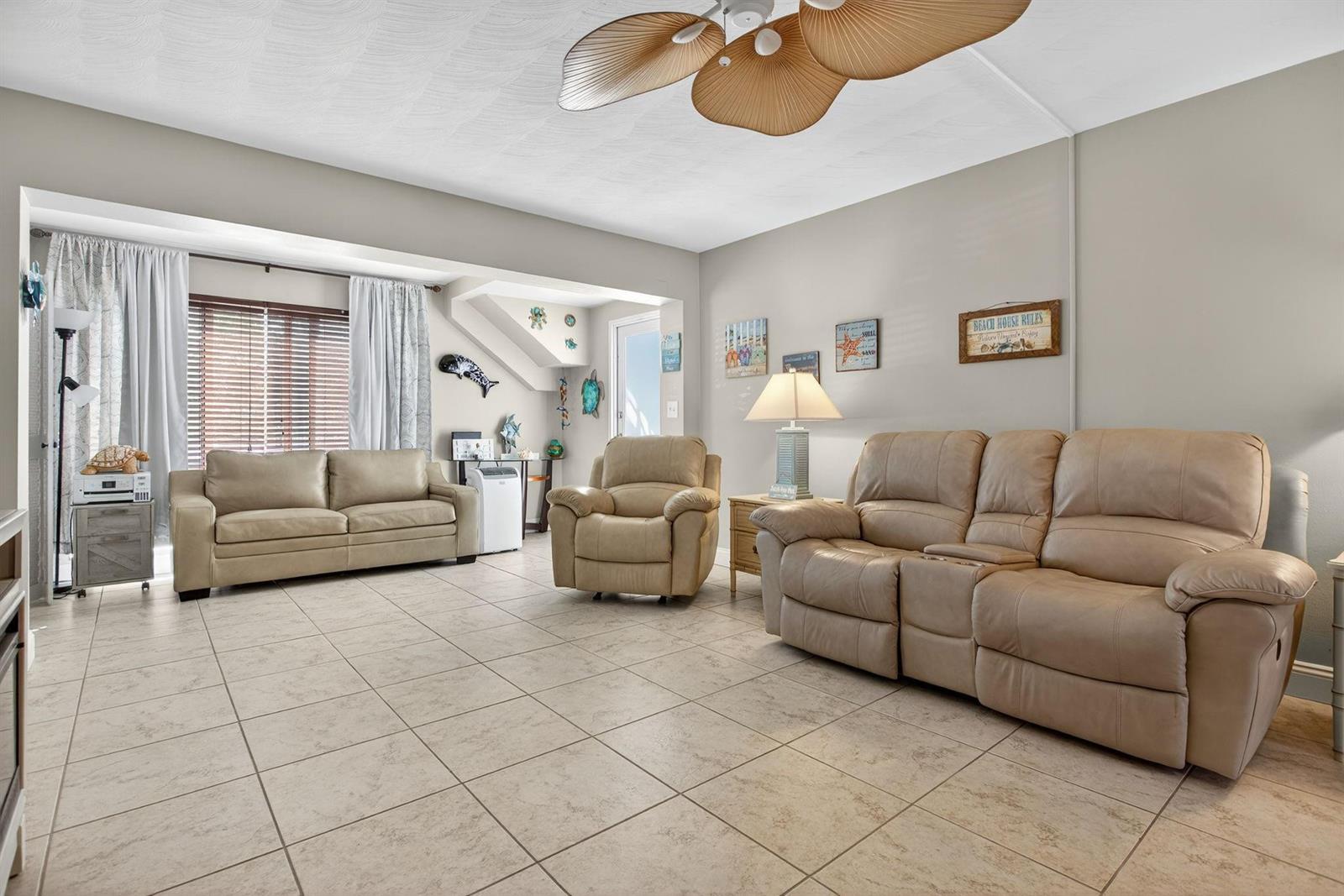 A living room with beige tile floors, three leather sofas, and a palm-leaf ceiling fan — 3201 SE 12th Street # C2, Pompano Beach FL 33062, POMPANO BEACH, FL
