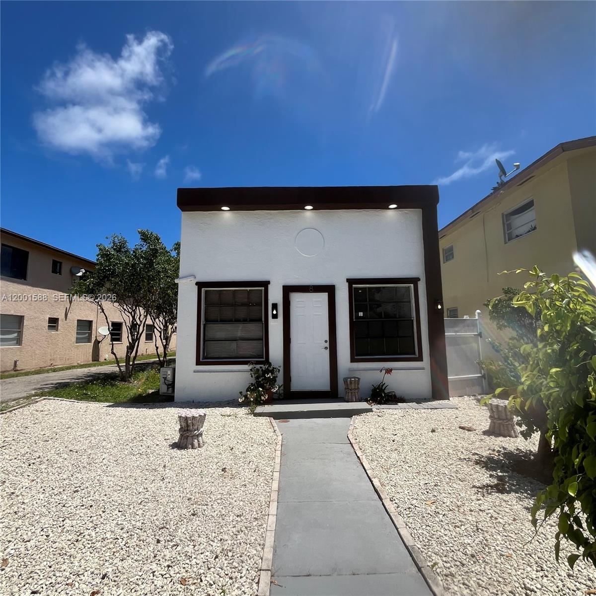 A small, white, single-story house with a flat roof and a gravel front yard — 8 S C St, Lake Worth FL 33460, LAKE WORTH, FL