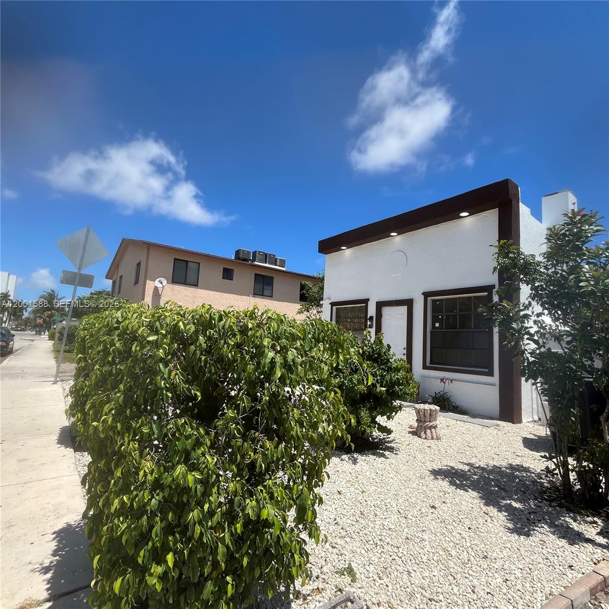 A white house with brown trim and a gravel yard sits next to a sidewalk — 8 S C St, Lake Worth FL 33460, LAKE WORTH, FL