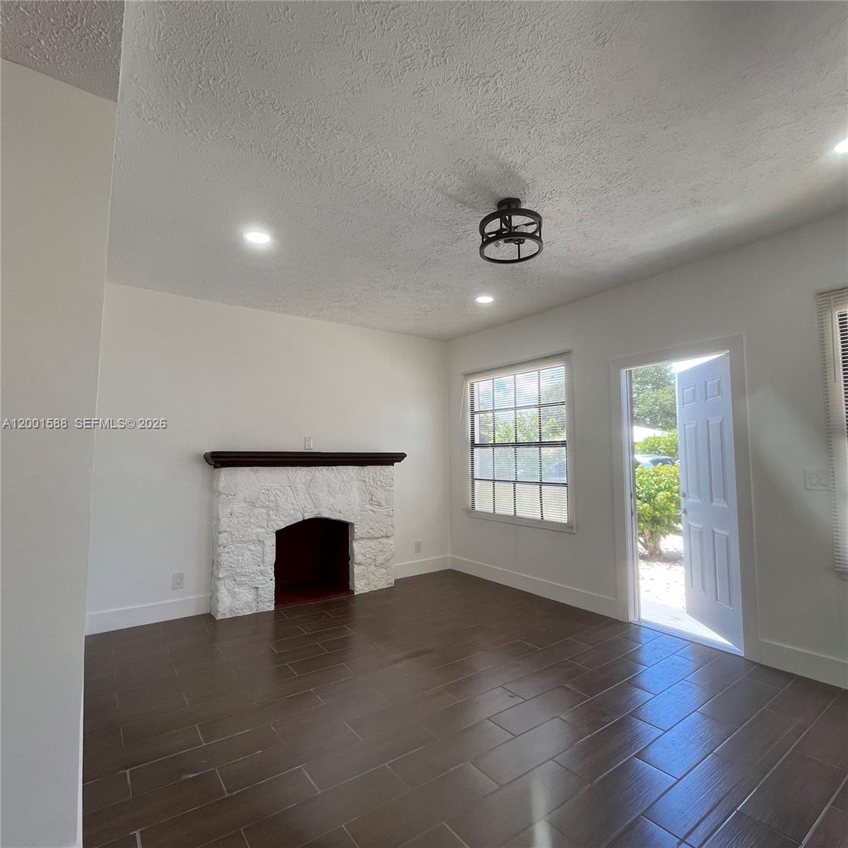 A living room features a white stone fireplace, dark tile flooring, and an open door — 8 S C St, Lake Worth FL 33460, LAKE WORTH, FL