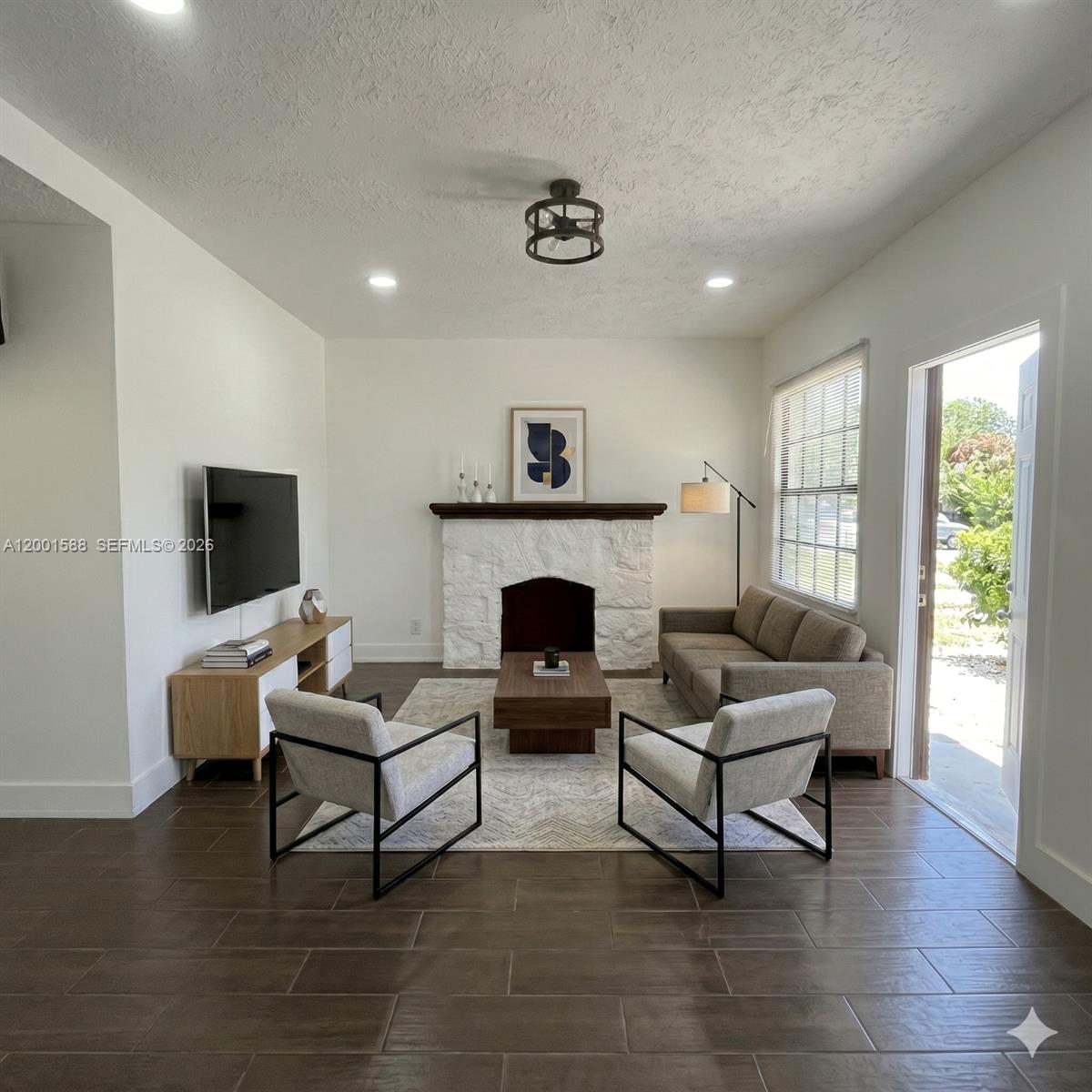 A living room features a white stone fireplace, wood-look tile flooring, and modern furniture — 8 S C St, Lake Worth FL 33460, LAKE WORTH, FL