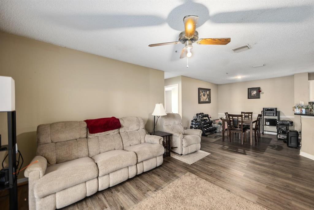 A living room with a beige sofa, recliner, dining set, and wood-look flooring — 4045 CROCKERS LAKE BOULEVARD UNIT 11, SARASOTA, FL