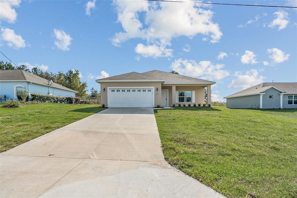 A single-story tan house with a two-car garage and a concrete driveway — 44 W LYNNHAVEN PLACE, CITRUS SPRINGS, FL
