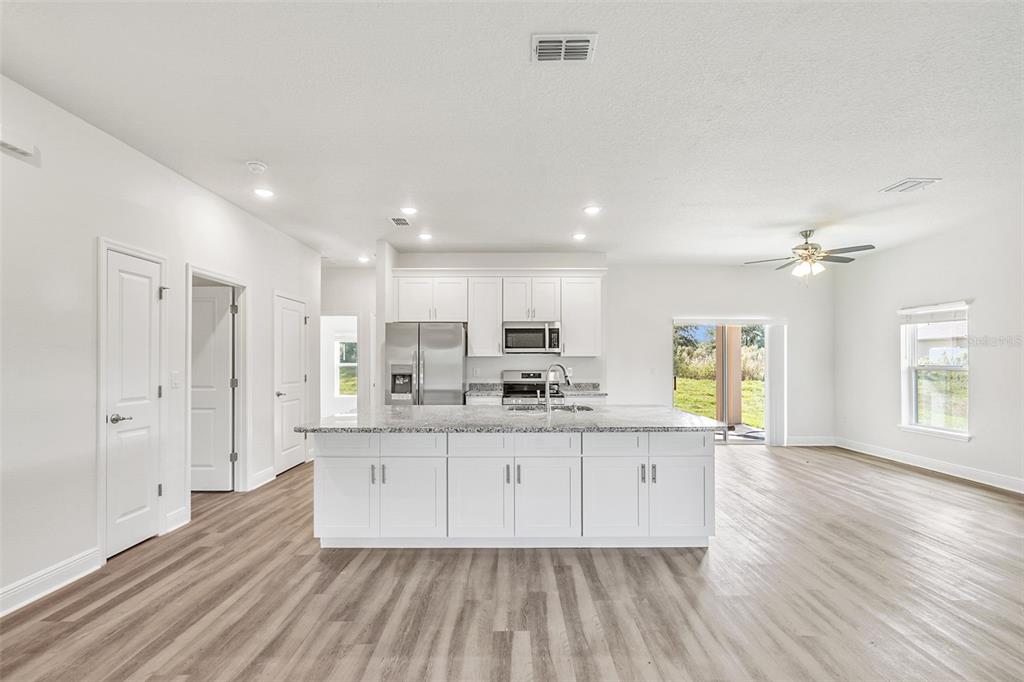 A modern kitchen with white cabinets, a granite island, and wood-look flooring in an open space — 44 W LYNNHAVEN PLACE, CITRUS SPRINGS, FL