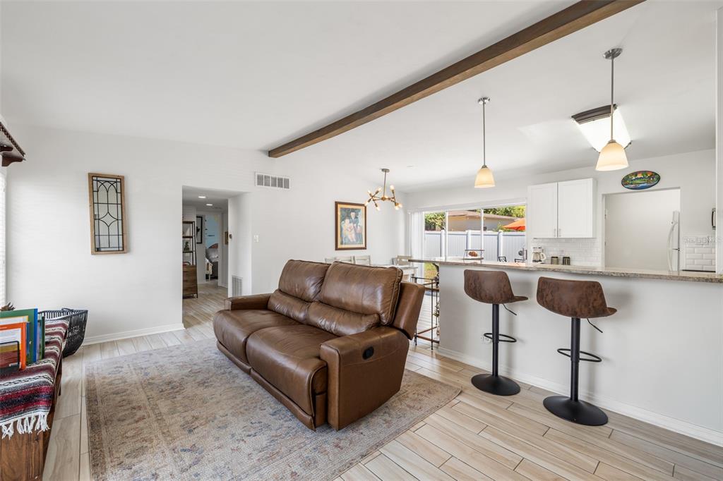 An open-concept living and dining area features light wood-look tile flooring and a kitchen peninsula — 2125 W HIAWATHA STREET, TAMPA, FL