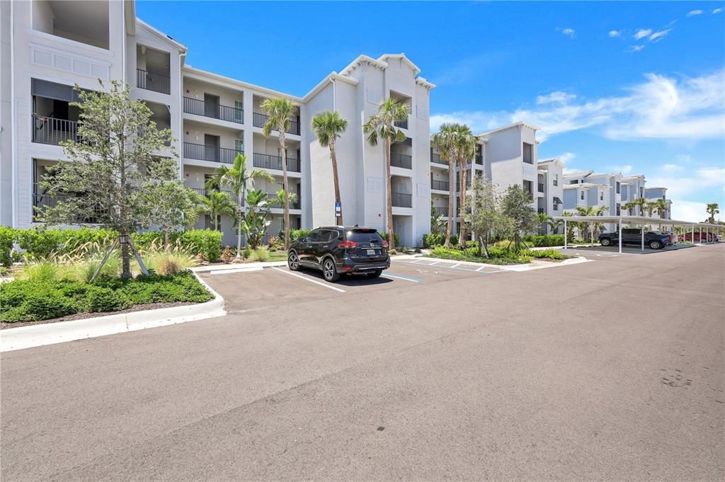 A multi-story apartment building with a parking lot and palm trees in front — 14051 HERITAGE LANDING BOULEVARD UNIT 524, PUNTA GORDA, FL