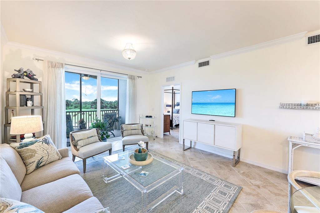 A bright living room features a beige sofa, two armchairs, a glass coffee table, and television — 14051 HERITAGE LANDING BOULEVARD UNIT 524, PUNTA GORDA, FL
